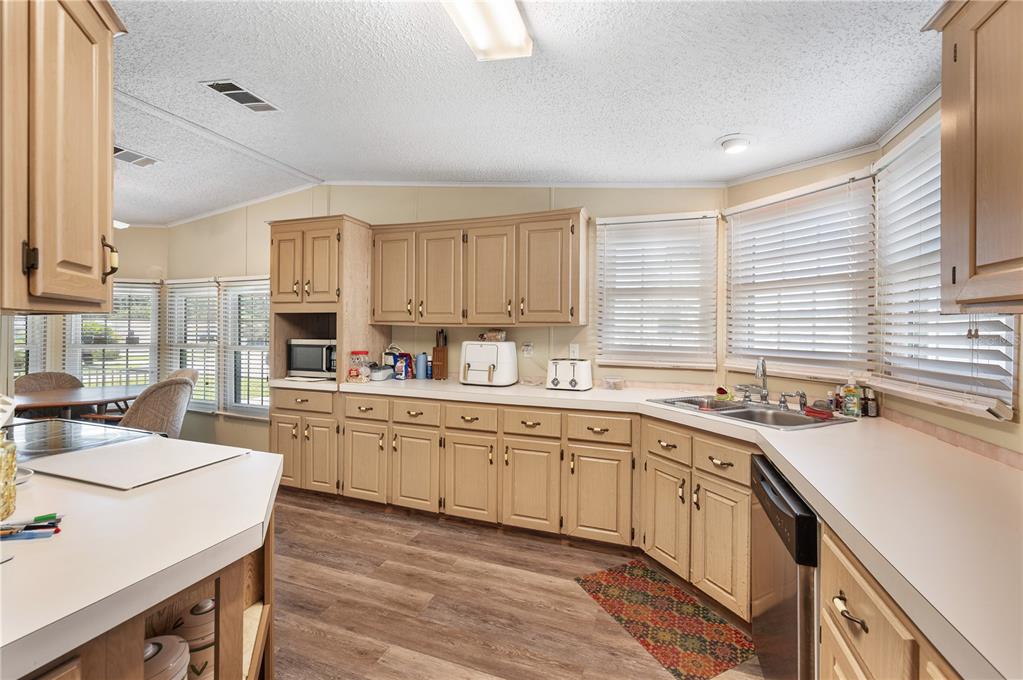 A kitchen features light wood cabinets, white countertops, a double sink, and wood-look flooring — 1610 REYNOLDS ROAD UNIT 333, LAKELAND, FL