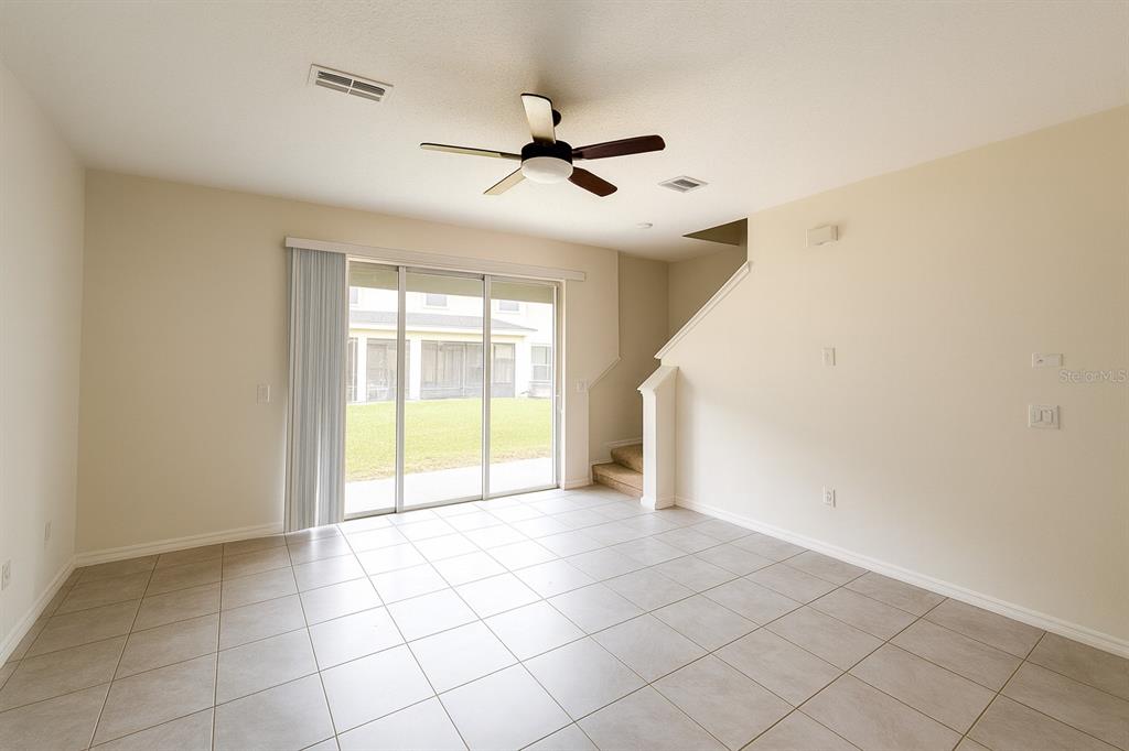 A living room with tile flooring, a ceiling fan, and sliding glass doors to a yard — 1288 YELLOW FINCH DRIVE, DAVENPORT, FL