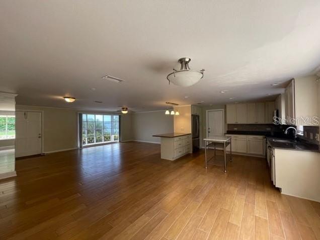 An open-concept kitchen and living area features light wood flooring and white cabinetry — 1326 LAKE ARIANA BOULEVARD, AUBURNDALE, FL