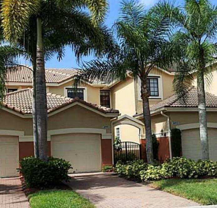A two-story residential building with a tiled roof, beige stucco walls, and two garage doors — 3890 Tree Top Drive, Weston FL 33332, WESTON, FL
