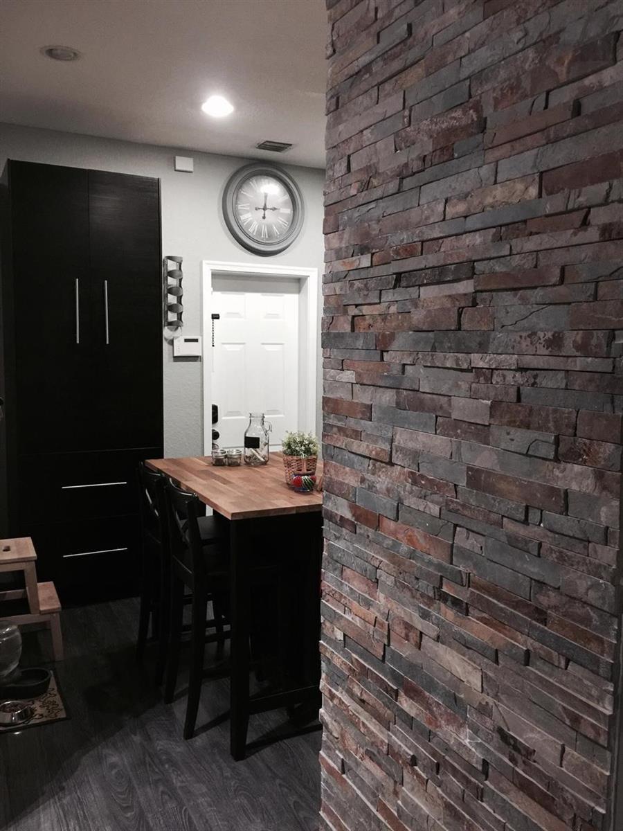 A kitchen area features a stone accent wall, dark cabinetry, and a wooden breakfast table — 3890 Tree Top Drive, Weston FL 33332, WESTON, FL