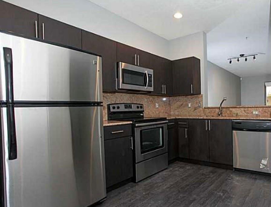 A kitchen features dark wood cabinets, stainless steel appliances, and granite countertops — 3890 Tree Top Drive, Weston FL 33332, WESTON, FL
