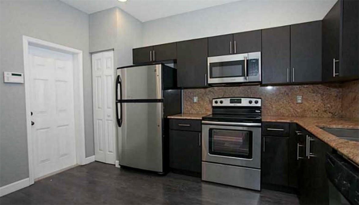 A kitchen features dark cabinetry, stainless steel appliances, and granite countertops — 3890 Tree Top Drive, Weston FL 33332, WESTON, FL
