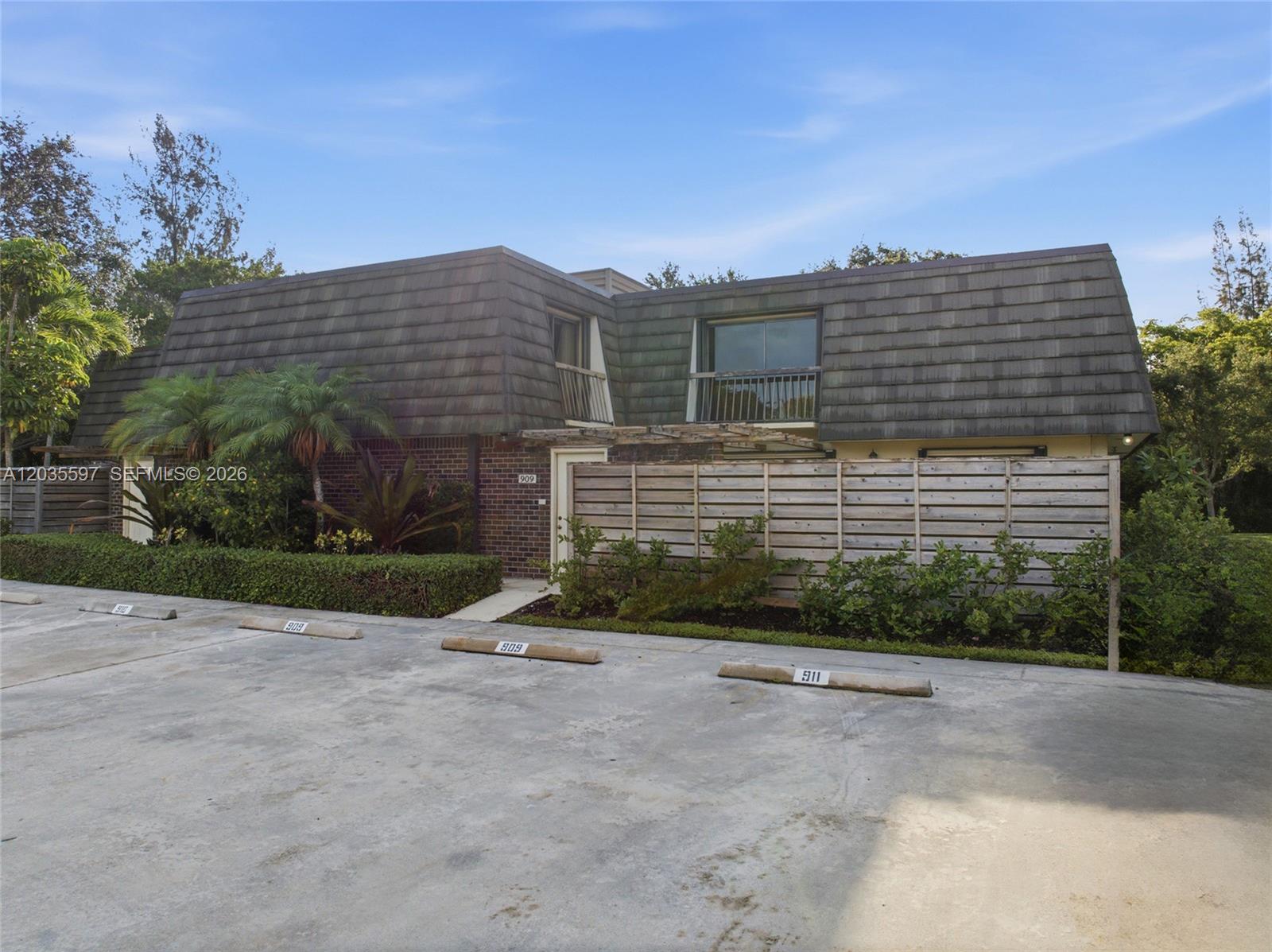 A two-story building with a mansard roof and a wooden privacy fence in the foreground — 909 9th Ter, Palm Beach Gardens FL 33418, PALM BEACH GARDENS, FL