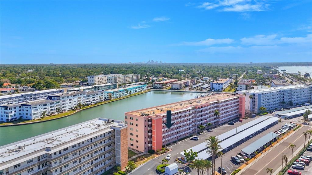 An aerial view shows a multi-story pink apartment building next to a canal — 6025 SHORE BOULEVARD S UNIT 303, GULFPORT, FL