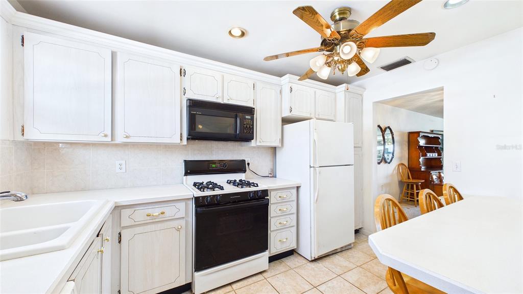 A kitchen features white cabinets, white appliances, a ceiling fan, and a breakfast bar — 6025 SHORE BOULEVARD S UNIT 303, GULFPORT, FL
