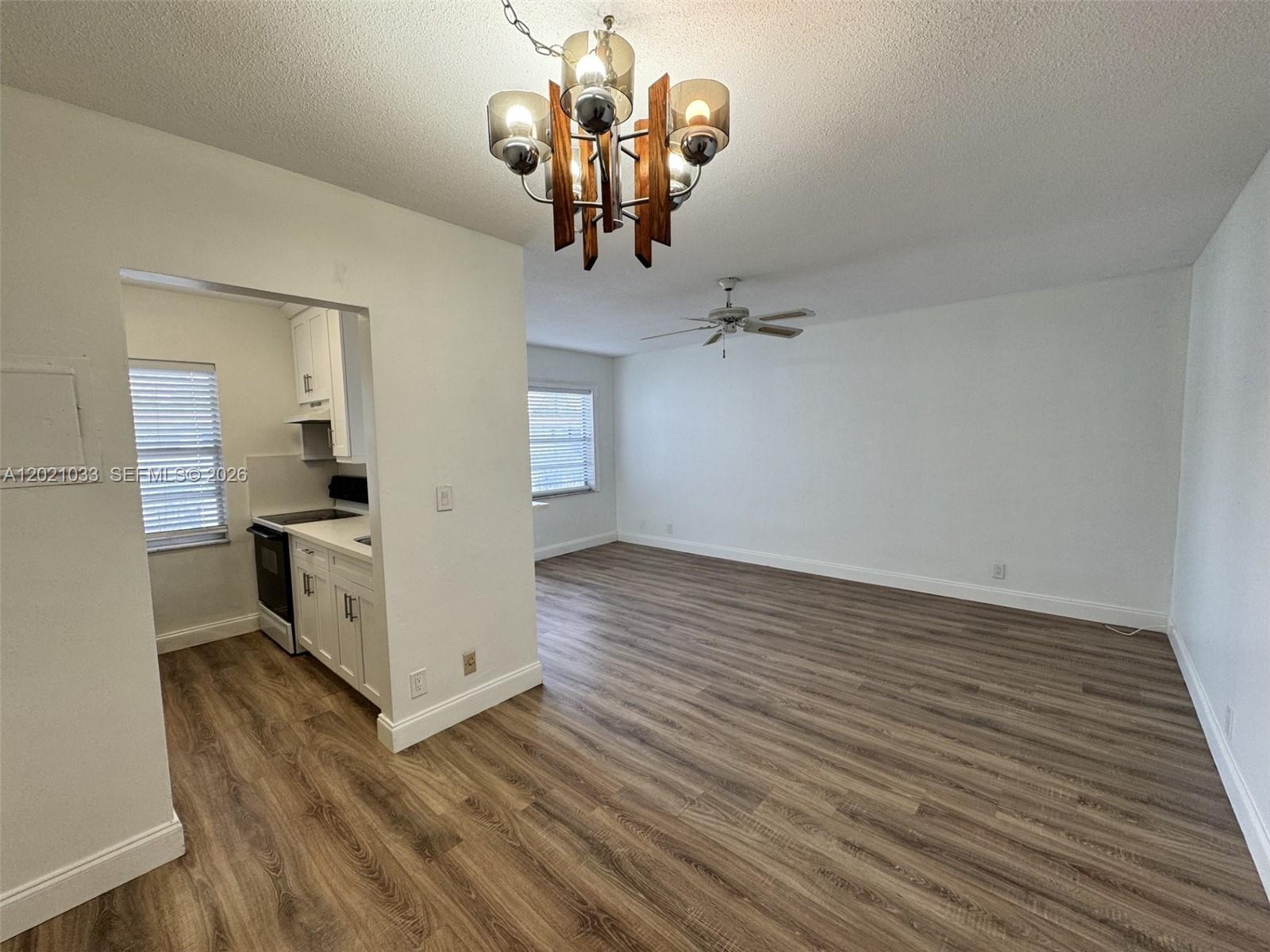 An open-concept living area features wood-look flooring, a ceiling fan, and an adjacent kitchen — 2219 Polk St # 4B, Hollywood FL 33020, HOLLYWOOD, FL