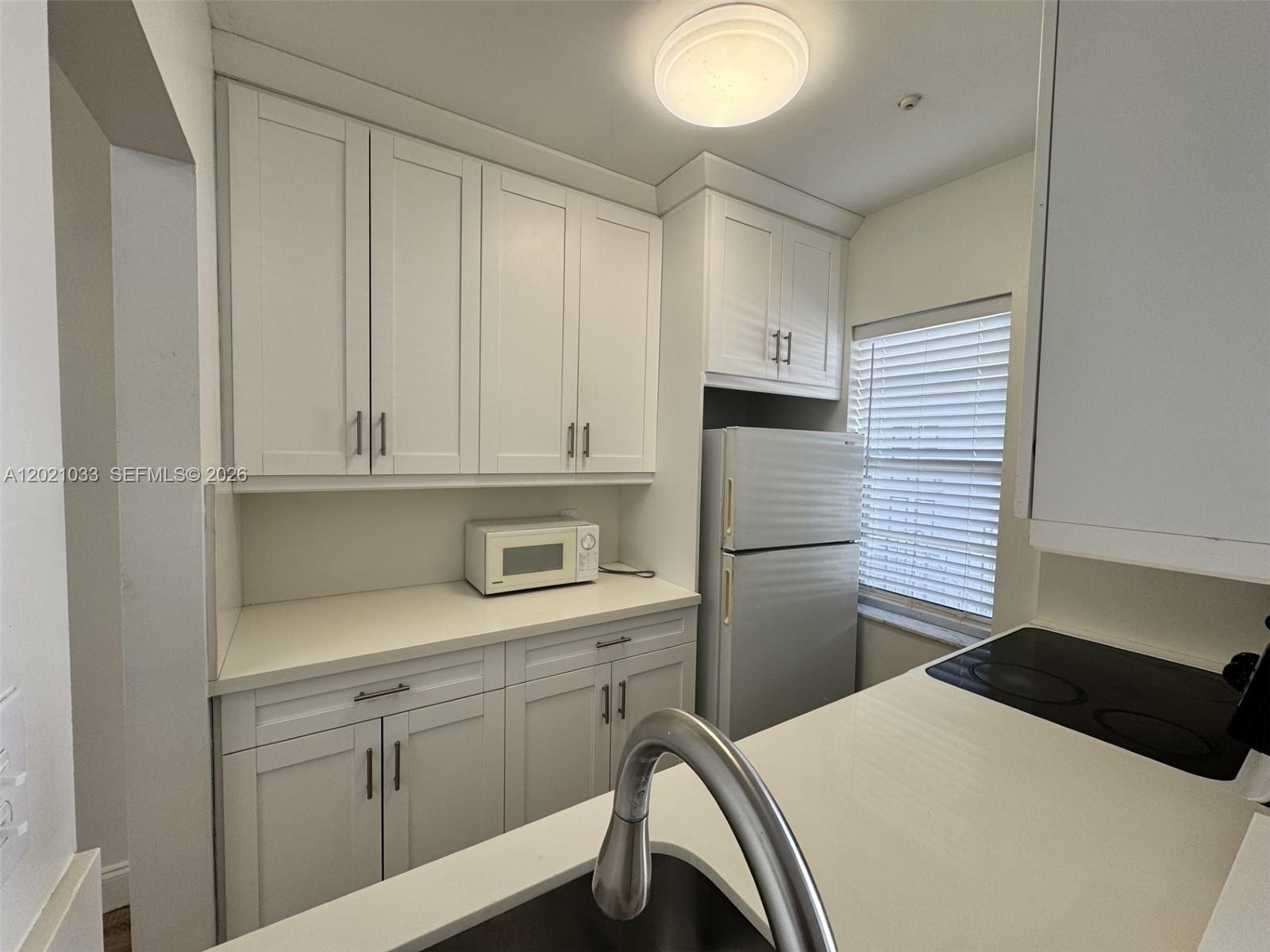 A kitchen features white cabinetry, quartz countertops, a stainless steel faucet, and a white refrigerator — 2219 Polk St # 4B, Hollywood FL 33020, HOLLYWOOD, FL