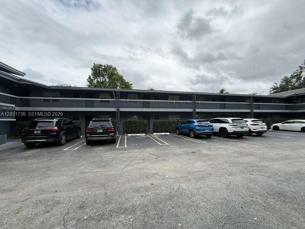 A two-story apartment building exterior features a parking lot with several parked cars — 8982 W Sample Rd # 204, Coral Springs FL 33065, CORAL SPRINGS, FL