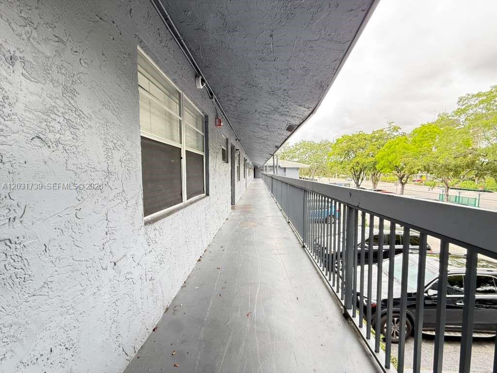 An exterior walkway with a metal railing overlooks a parking lot with trees — 8982 W Sample Rd # 204, Coral Springs FL 33065, CORAL SPRINGS, FL