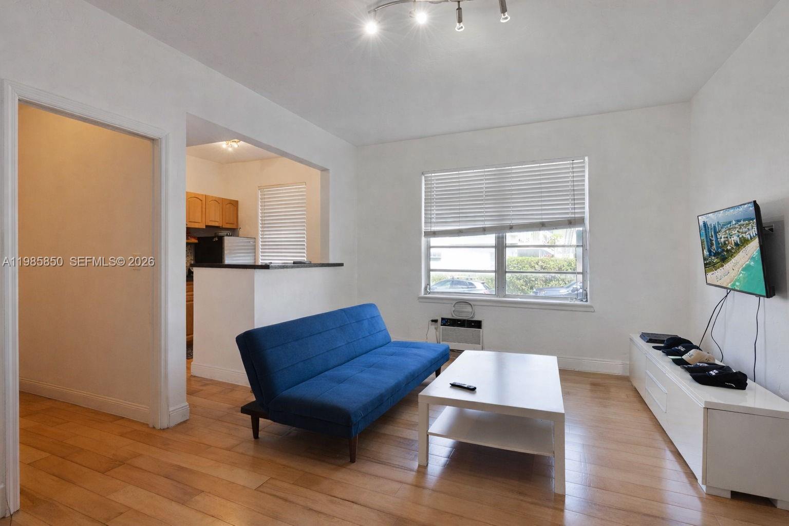 A living room features a blue sofa, white coffee table, media console, and wood flooring — 760 Jefferson Ave # 5, Miami Beach FL 33139, MIAMI BEACH, FL