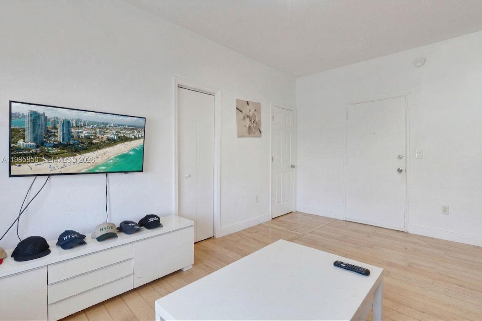 A living room features a wall-mounted television, white media console, and light wood flooring — 760 Jefferson Ave # 5, Miami Beach FL 33139, MIAMI BEACH, FL