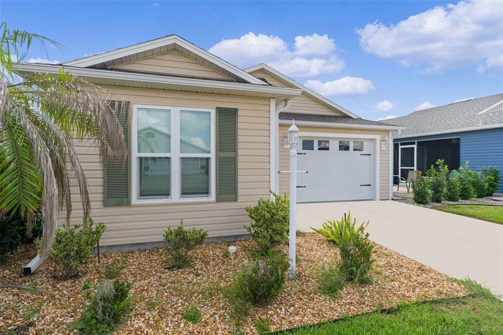 A tan, single-story house with a white garage door and green shutters — 5415 ZAJAC AVENUE, THE VILLAGES, FL