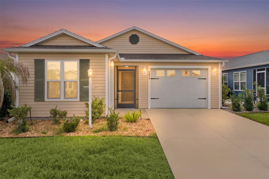 A single-story tan house with a garage, a front lawn, and a sunset sky — 5415 ZAJAC AVENUE, THE VILLAGES, FL
