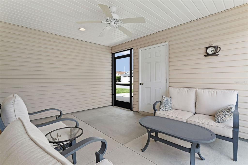 A covered patio features beige siding, a ceiling fan, a screen door, and outdoor furniture — 5415 ZAJAC AVENUE, THE VILLAGES, FL