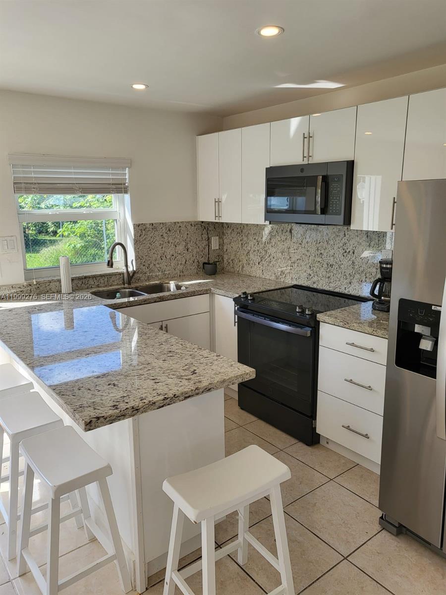 An empty room features white walls, tile flooring, a window with blinds, and a wall-mounted air conditioner — HOLLYWOOD, FL