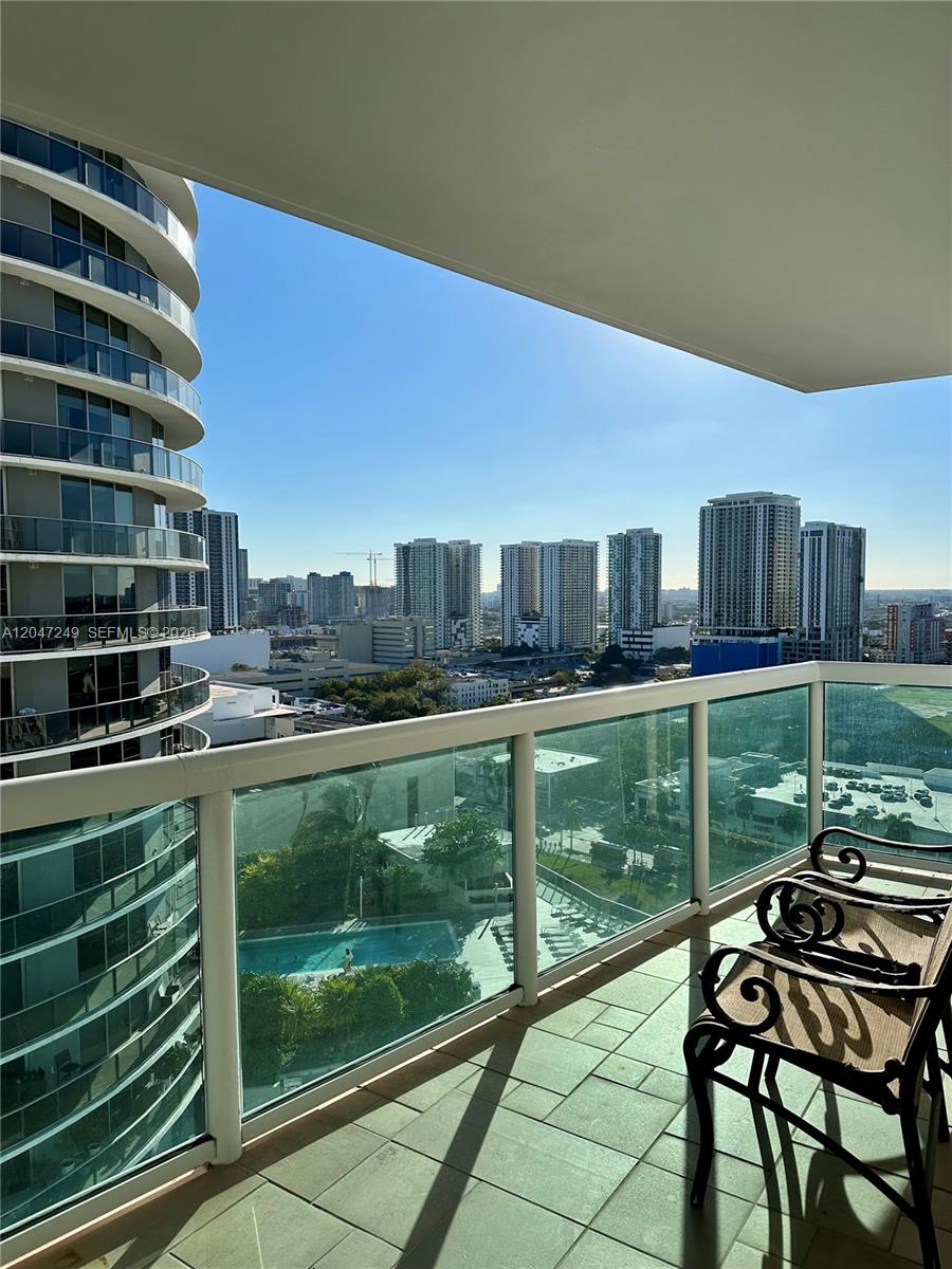 A balcony with metal chairs overlooks a swimming pool and a city skyline — 1800 N Bayshore Dr # 2315, Miami FL 33132, MIAMI, FL