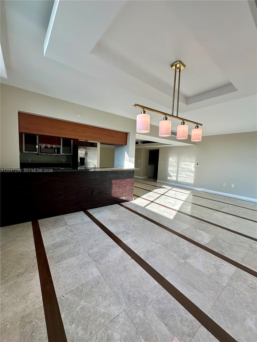 A kitchen with a dark stone breakfast bar sits adjacent to a tiled dining area — 1800 N Bayshore Dr # 2315, Miami FL 33132, MIAMI, FL