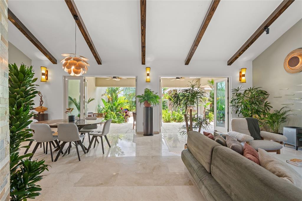 A bright living and dining area features vaulted ceilings with exposed beams and glass doors — 319 CAMINO DEL GUAMA, DORADO, PR
