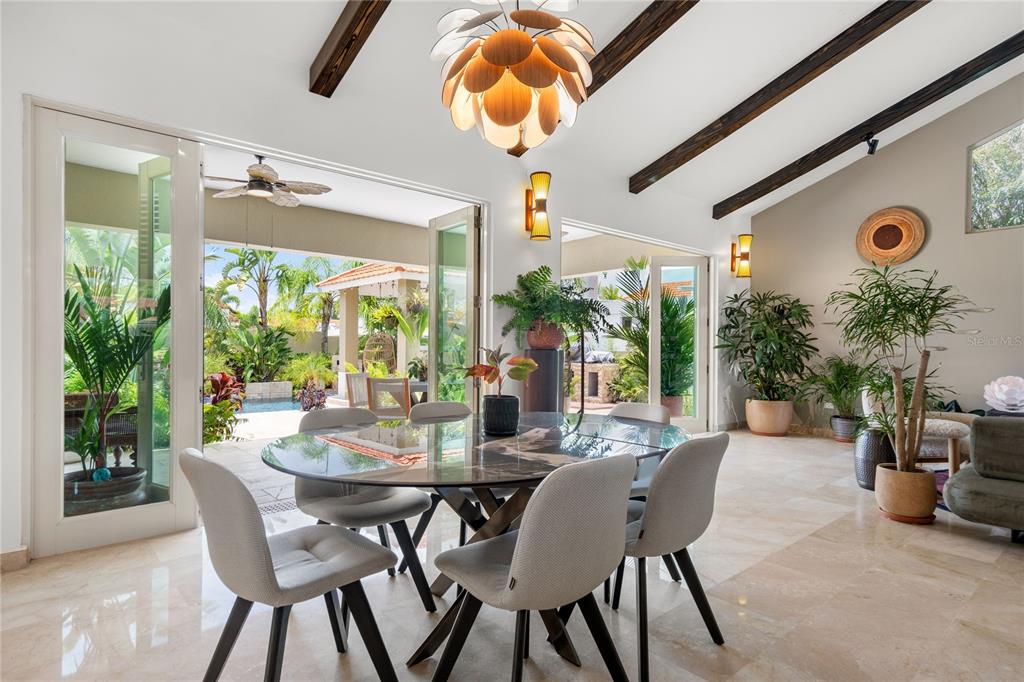 A dining room with a glass table, exposed wood beams, and large doors opening outdoors — 319 CAMINO DEL GUAMA, DORADO, PR