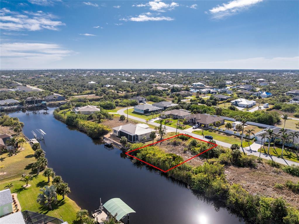 An aerial view shows a vacant waterfront lot outlined in red next to a residential street — 14534 MAYSVILLE CIRCLE, PORT CHARLOTTE, FL