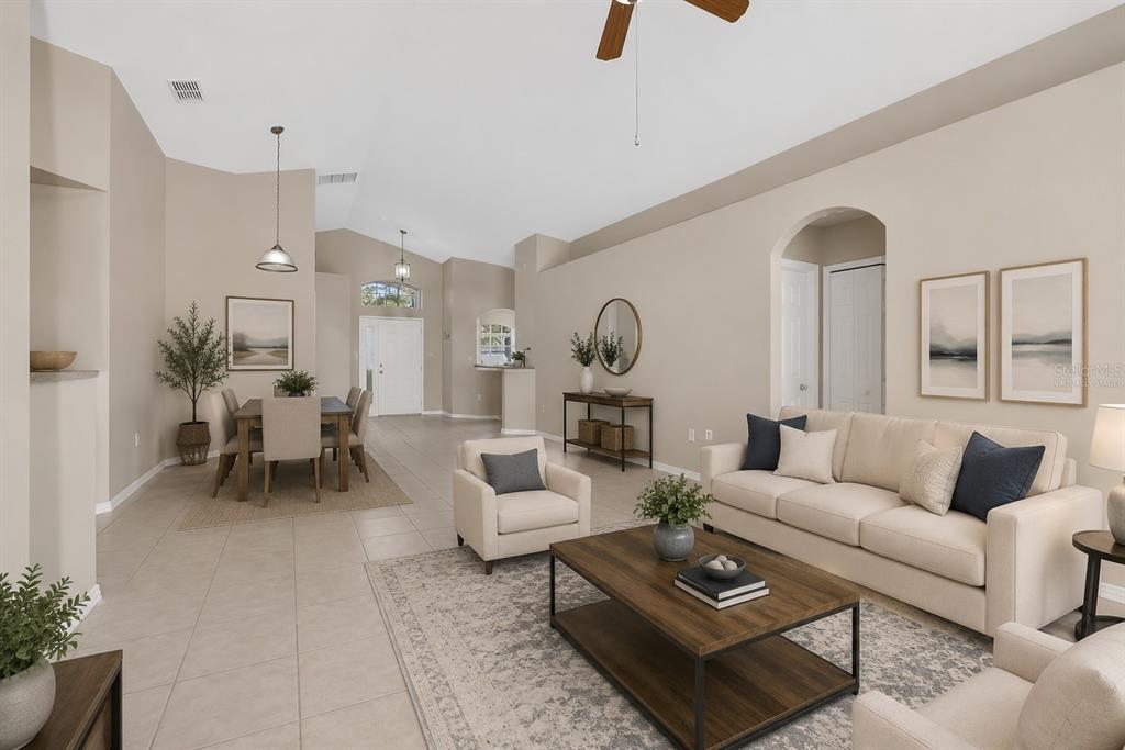 A living and dining room with tile floors, neutral walls, and a vaulted ceiling — 348 SIR PHILLIPS DRIVE, DAVENPORT, FL
