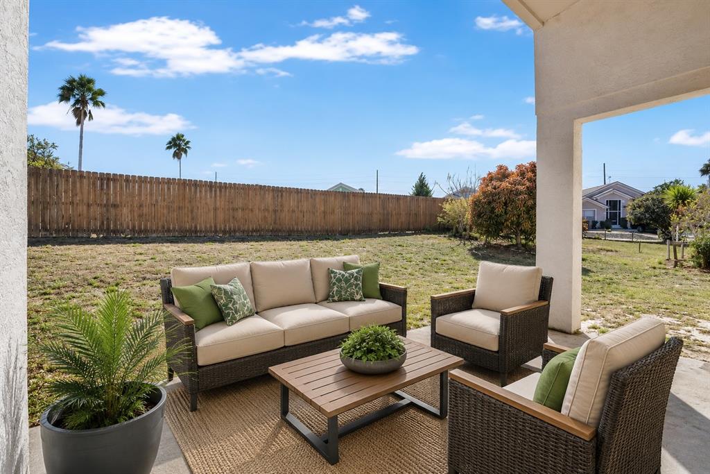 A patio with wicker furniture and a coffee table overlooks a fenced backyard — 348 SIR PHILLIPS DRIVE, DAVENPORT, FL