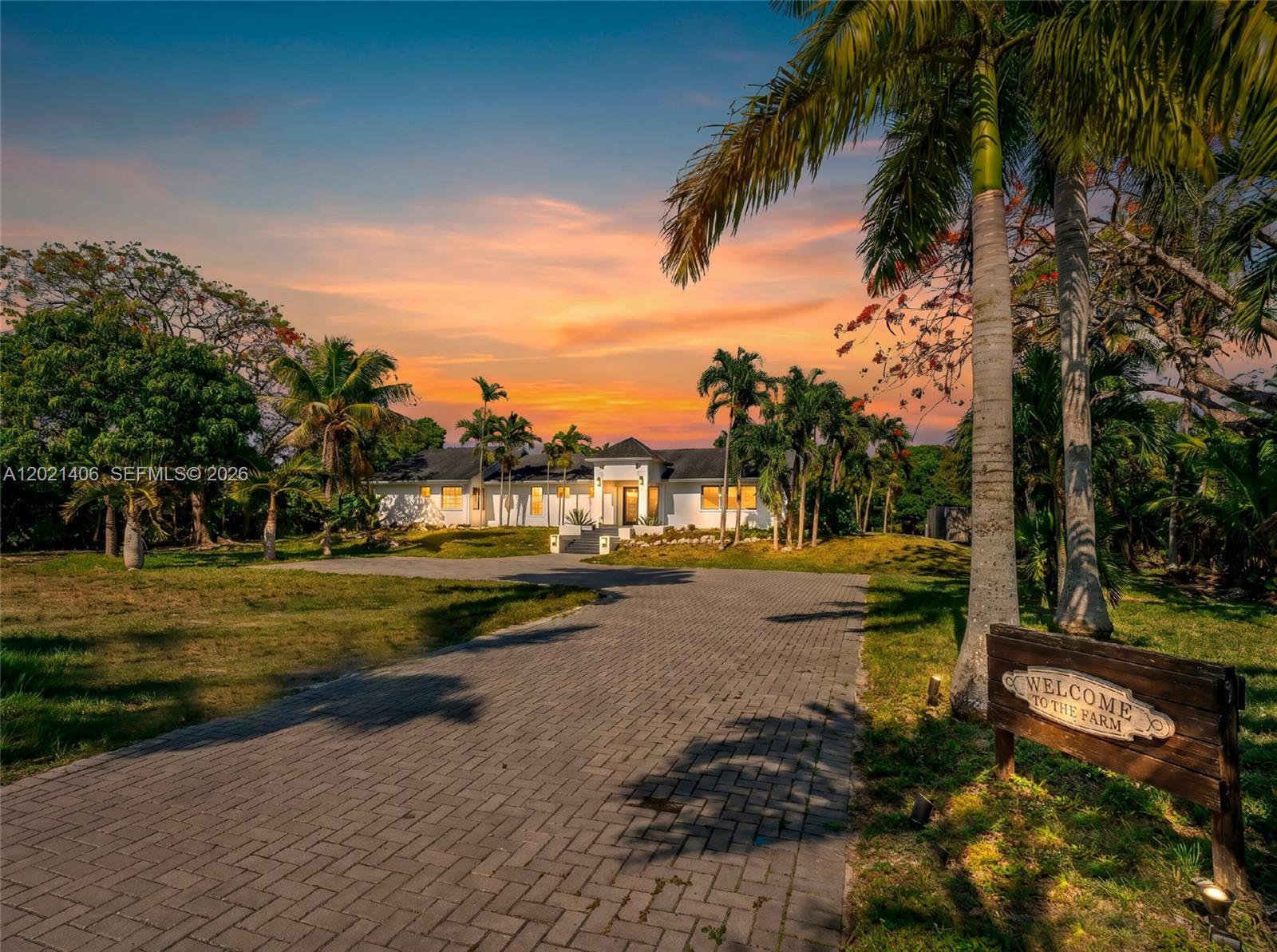 A paved driveway leads to a white house surrounded by palm trees at sunset — 19601 SW 187th Ave, Miami FL 33187, MIAMI, FL