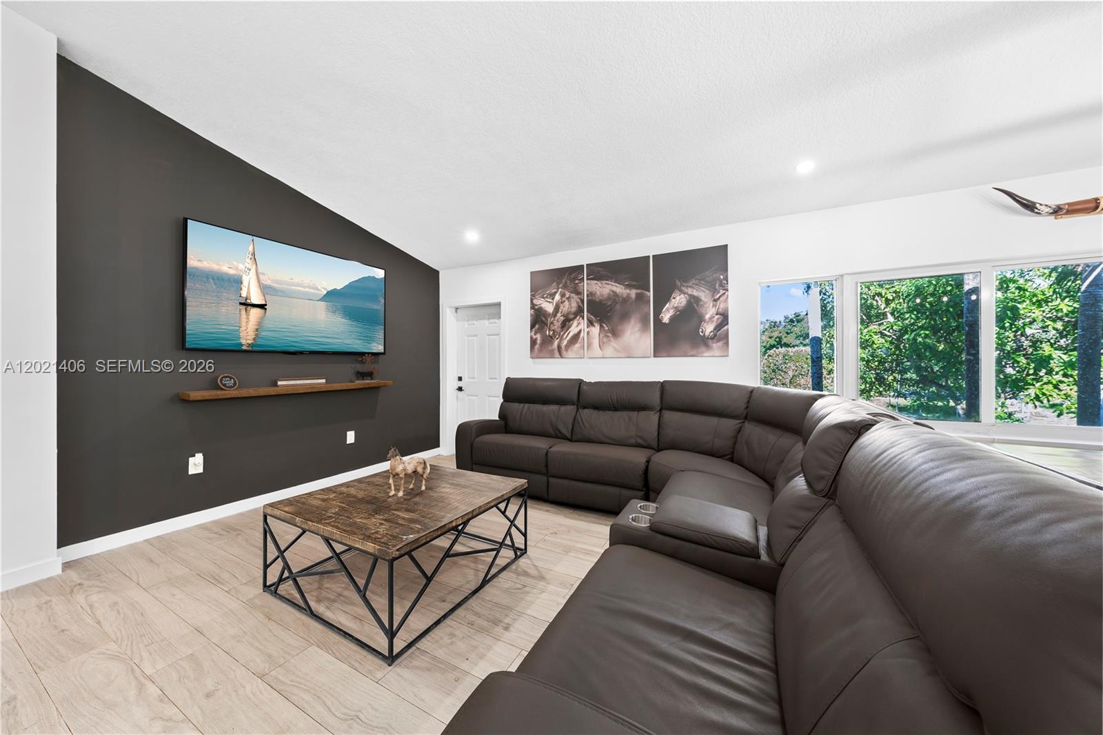 A living room features a dark accent wall, a large sectional sofa, and wood-look flooring — 19601 SW 187th Ave, Miami FL 33187, MIAMI, FL