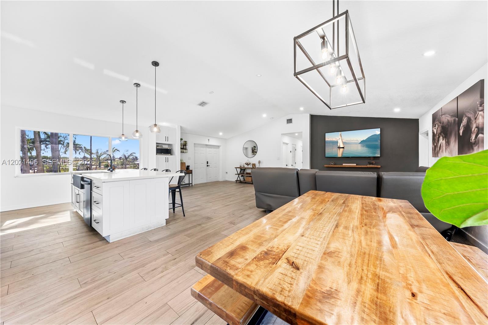 An open-concept kitchen and living area features light wood flooring and a large island — 19601 SW 187th Ave, Miami FL 33187, MIAMI, FL