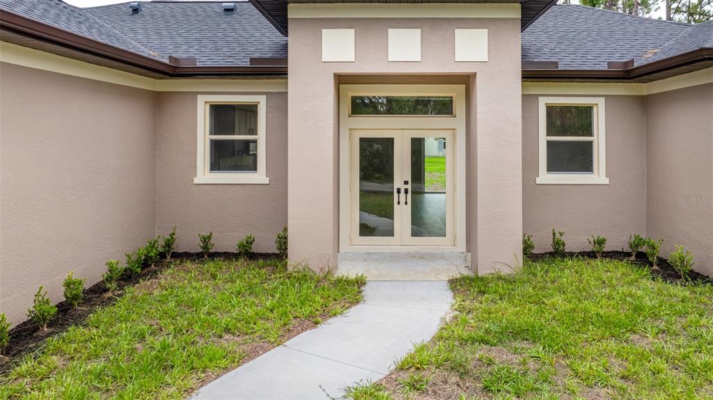 The exterior of a tan house features a double front door and a concrete walkway — 2635 SNUG STREET, NORTH PORT, FL