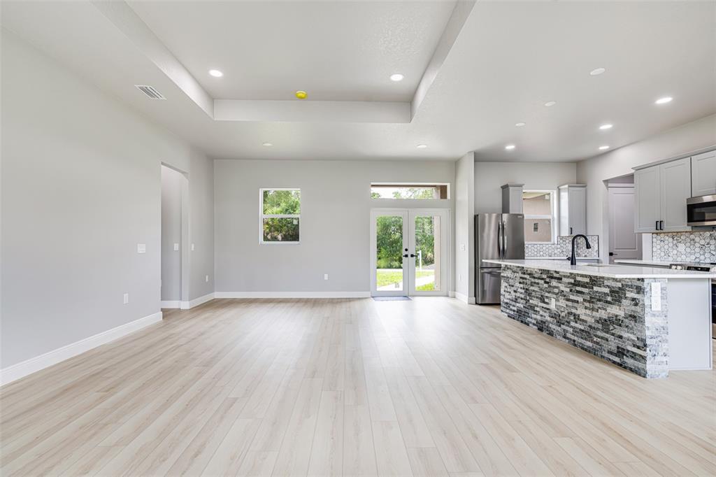 An open-concept living area features light wood-look flooring, a tray ceiling, and a stone-faced island — 2635 SNUG STREET, NORTH PORT, FL