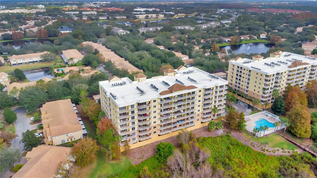 An aerial view shows two multi-story apartment buildings situated near a large lake — 6336 BUFORD STREET UNIT 405, ORLANDO, FL