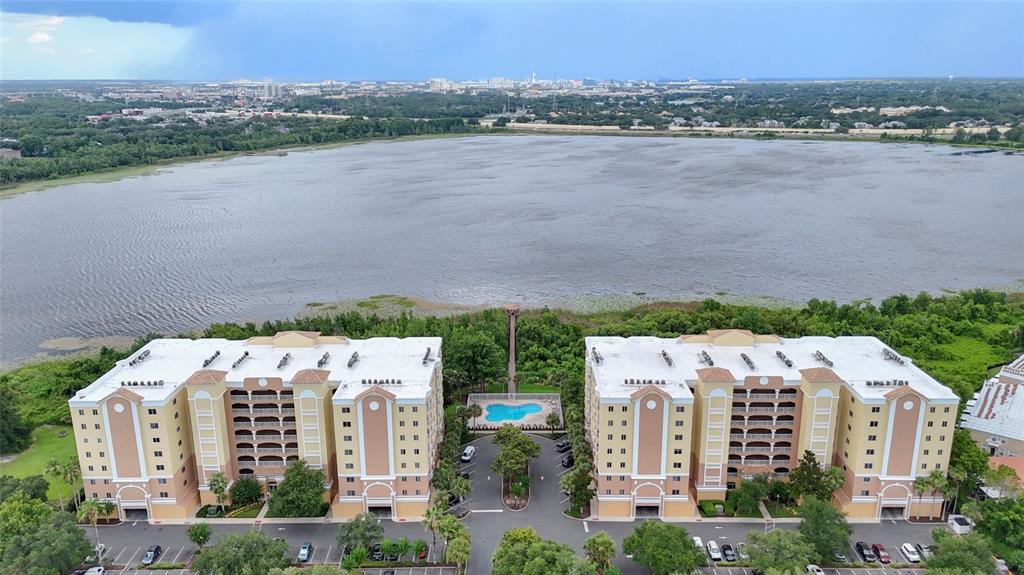 An aerial view shows two large apartment buildings situated beside a lake with a pool — 6312 BUFORD STREET UNIT 708, ORLANDO, FL
