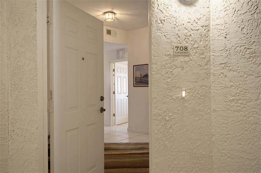 An open white door reveals an entryway with tile flooring and a view into another room — 6312 BUFORD STREET UNIT 708, ORLANDO, FL