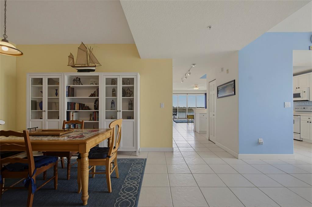A dining area with a wooden table and white cabinets leads to a bright living space — 6312 BUFORD STREET UNIT 708, ORLANDO, FL