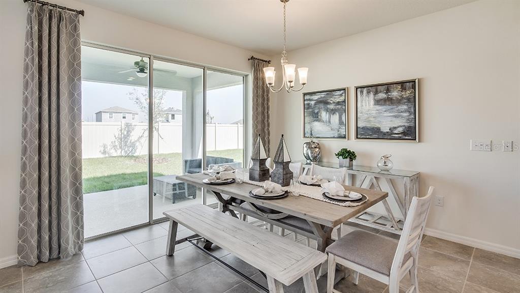 A dining room features a wooden table with a bench, chairs, and a sliding glass door — 6849 FLINT CREEK DRIVE, LAND O LAKES, FL