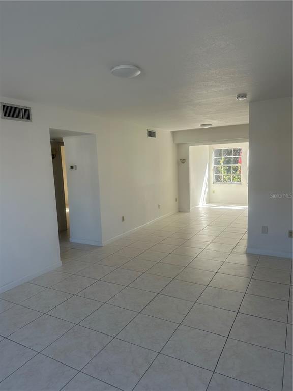 An empty living area features white walls, tiled flooring, and a window at the far end — 4158 TAMIAMI TRAIL UNIT B1, PORT CHARLOTTE, FL