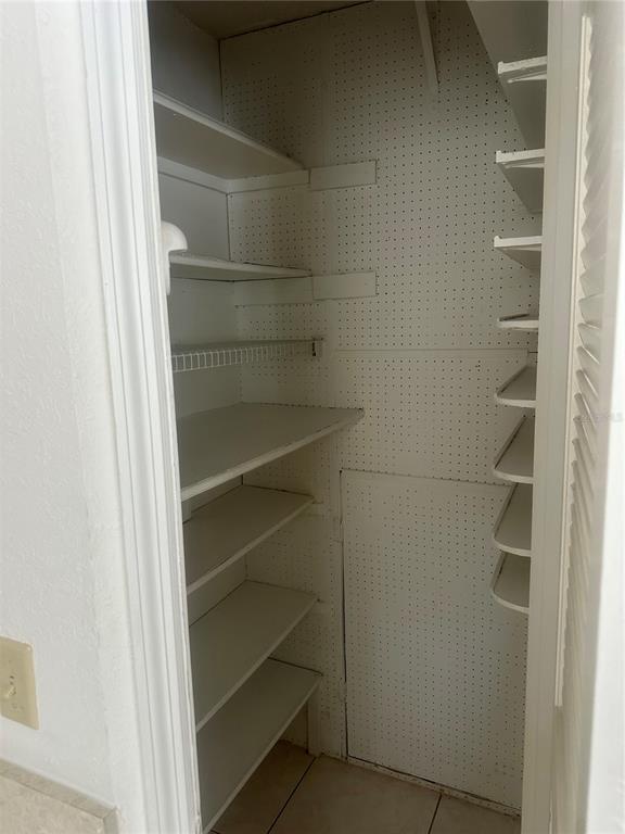 A pantry closet features white shelving, pegboard walls, and a louvered door — 4158 TAMIAMI TRAIL UNIT B1, PORT CHARLOTTE, FL