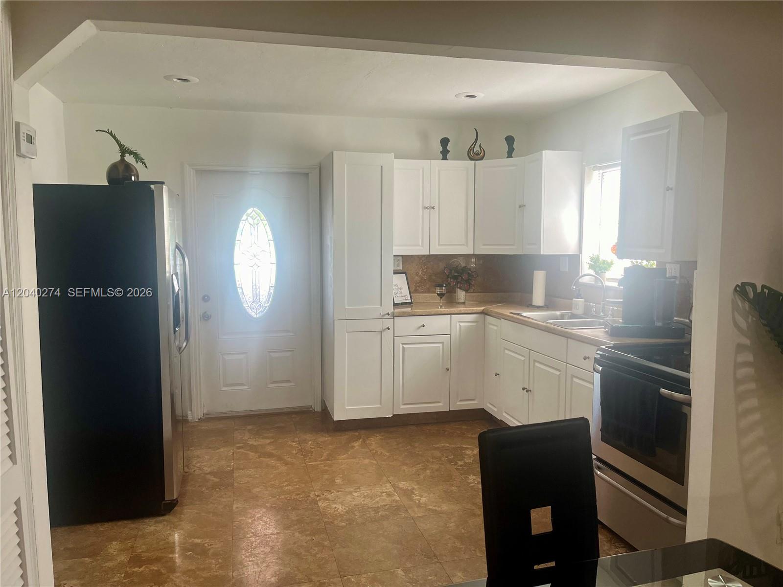 A kitchen features white cabinets, stainless steel appliances, and tan tile flooring — 521 NW 32nd Pl, Miami FL 33125, MIAMI, FL