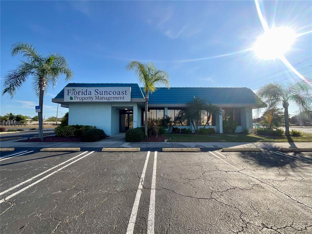 A commercial building with a blue roof and palm trees sits behind a parking lot — 473 S INDIANA AVENUE, ENGLEWOOD, FL