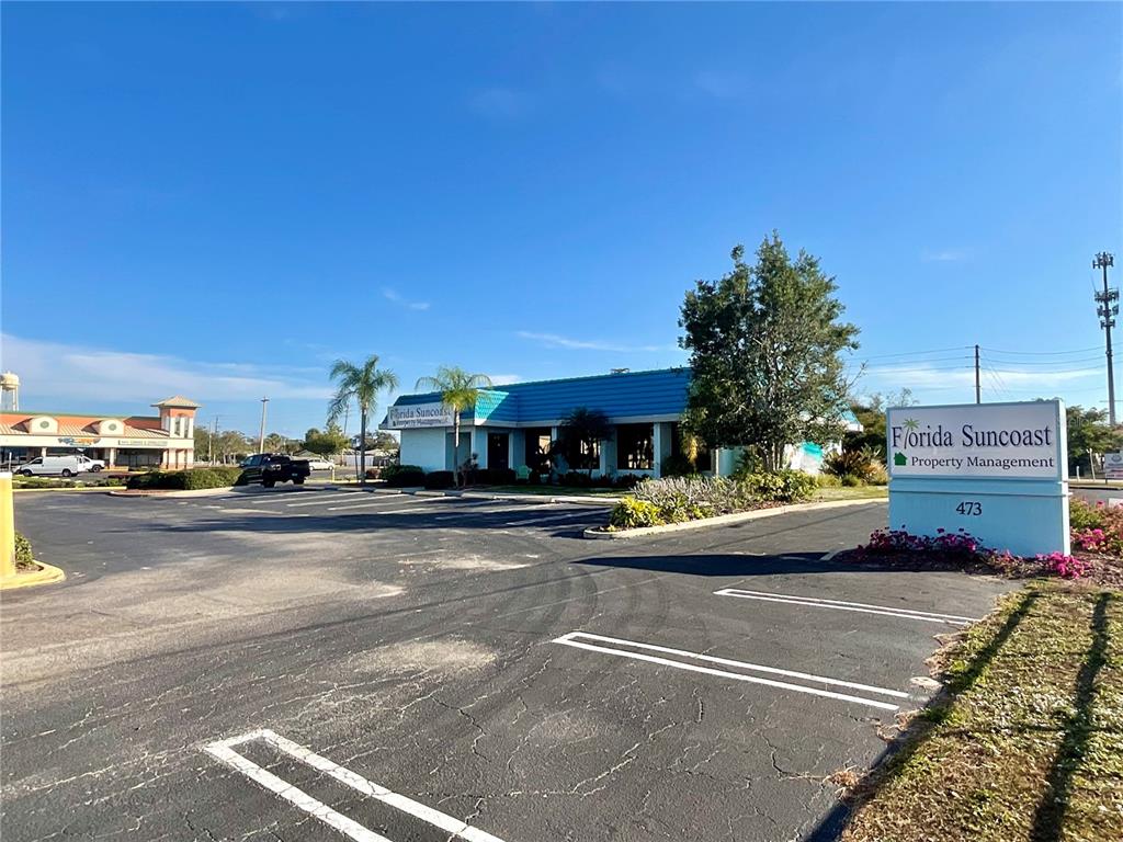 A commercial building with a blue roof and a sign for Florida Suncoast Property Management — 473 S INDIANA AVENUE, ENGLEWOOD, FL