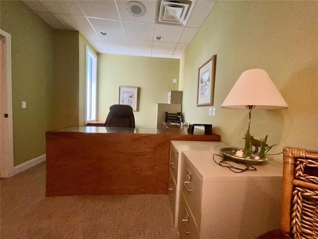 An office features a wooden desk, a beige filing cabinet, and a lamp on a table — 473 S INDIANA AVENUE, ENGLEWOOD, FL