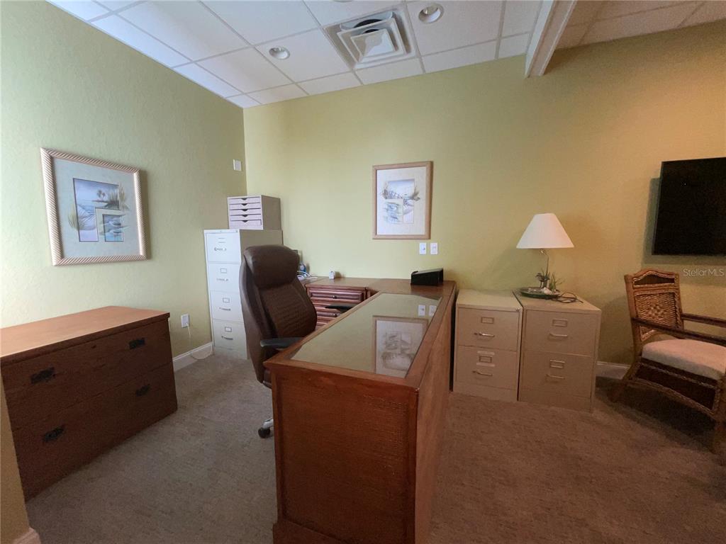 A home office features a wooden desk, a rolling chair, filing cabinets, and wall art — 473 S INDIANA AVENUE, ENGLEWOOD, FL