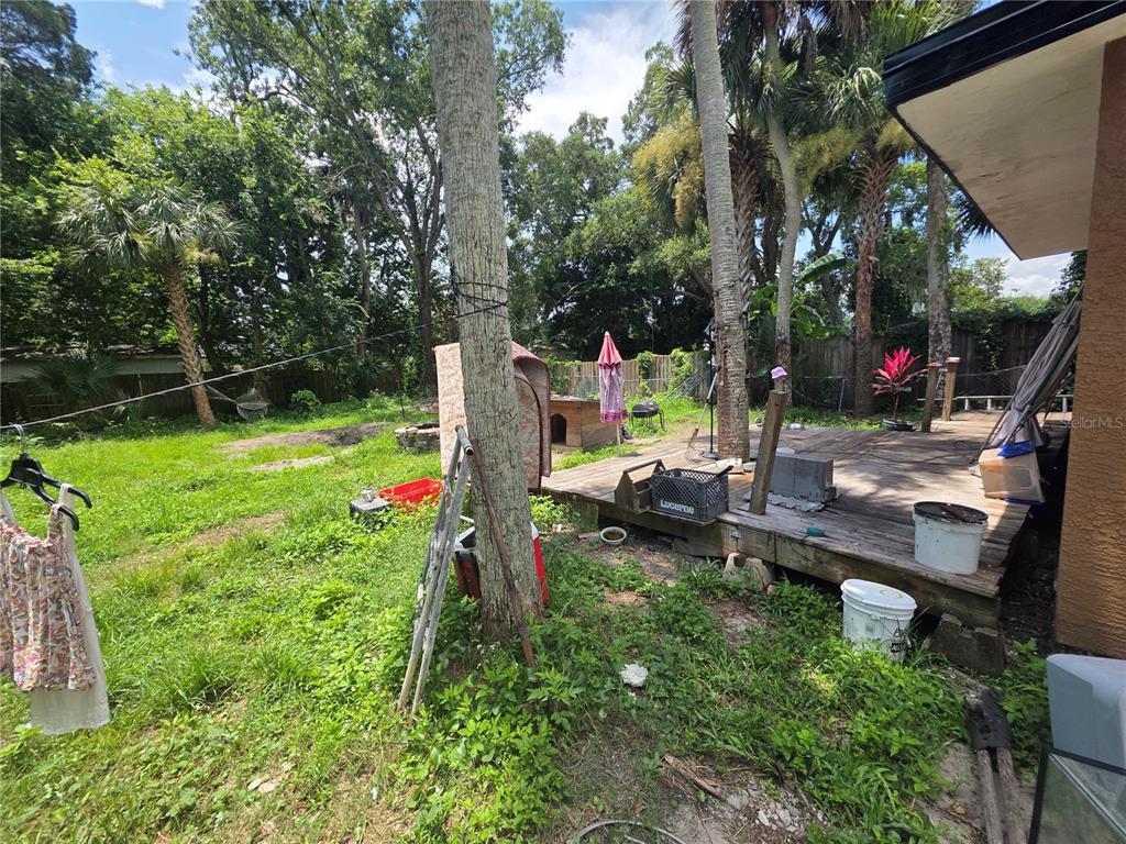 A backyard features a wooden deck, a grassy lawn, several trees, and various outdoor items — 625 AURORA STREET, SOUTH DAYTONA, FL