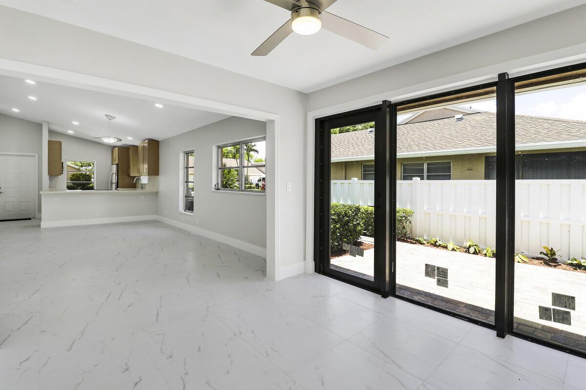 A bright room with white marble-look tile floors, a ceiling fan, and black-framed glass doors — 8157 Springtree Road, Boca Raton FL 33496, BOCA RATON, FL