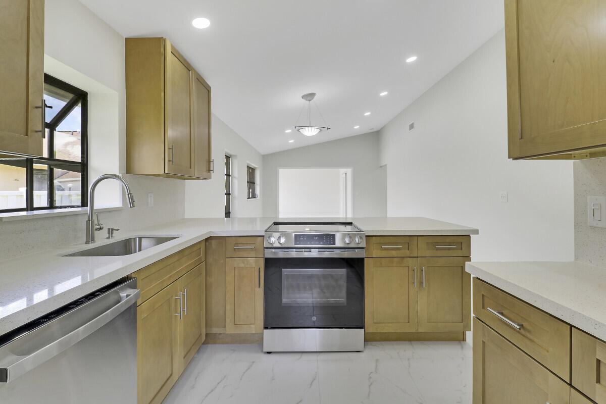 A kitchen features light wood cabinets, white countertops, stainless steel appliances, and white tile flooring — 8157 Springtree Road, Boca Raton FL 33496, BOCA RATON, FL