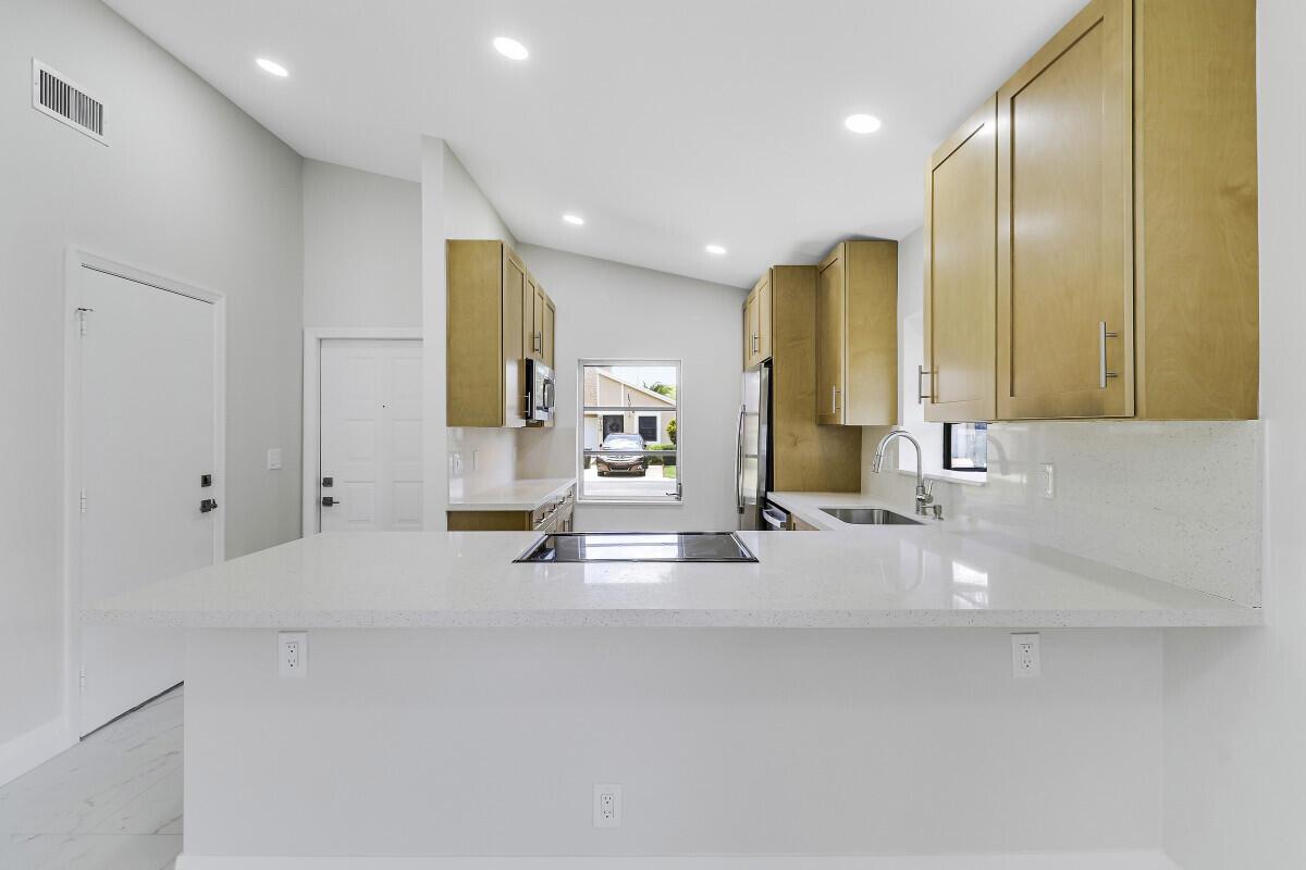 A kitchen with light wood cabinets, white quartz countertops, and a breakfast bar — 8157 Springtree Road, Boca Raton FL 33496, BOCA RATON, FL