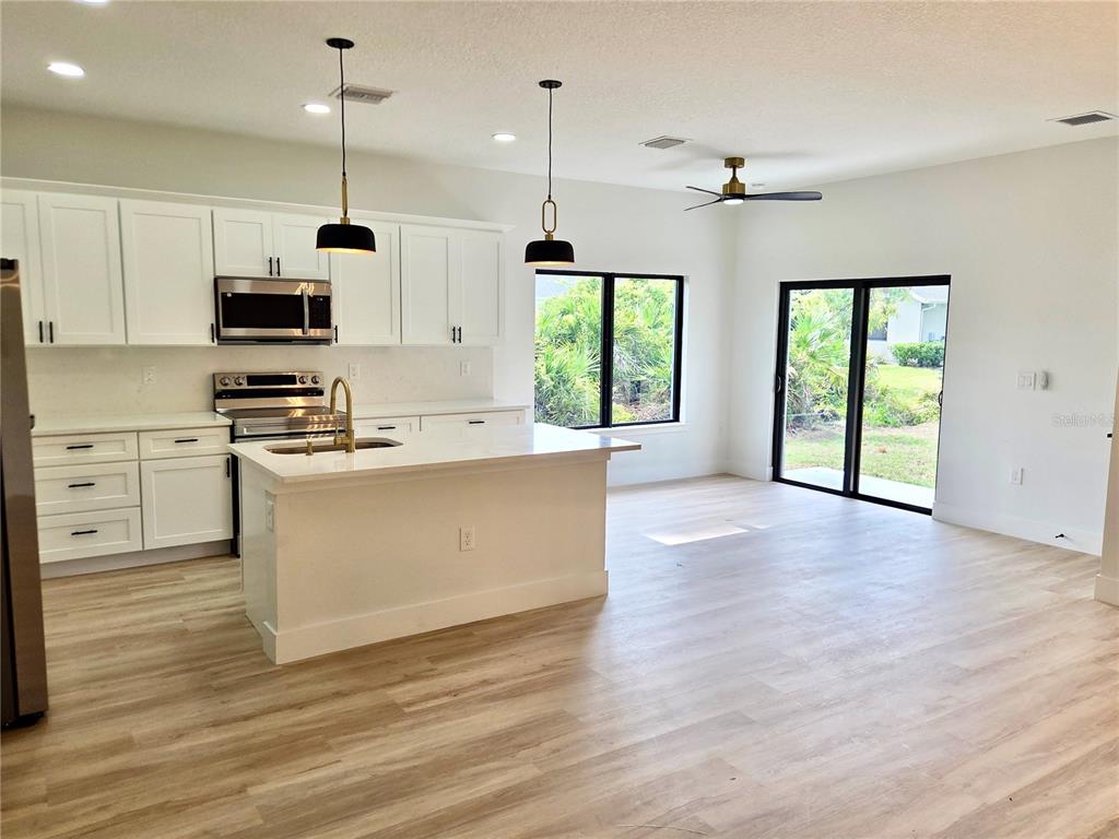 A modern kitchen with white cabinets, a central island, and light wood flooring — 138 INGRAM BOULEVARD, ROTONDA WEST, FL