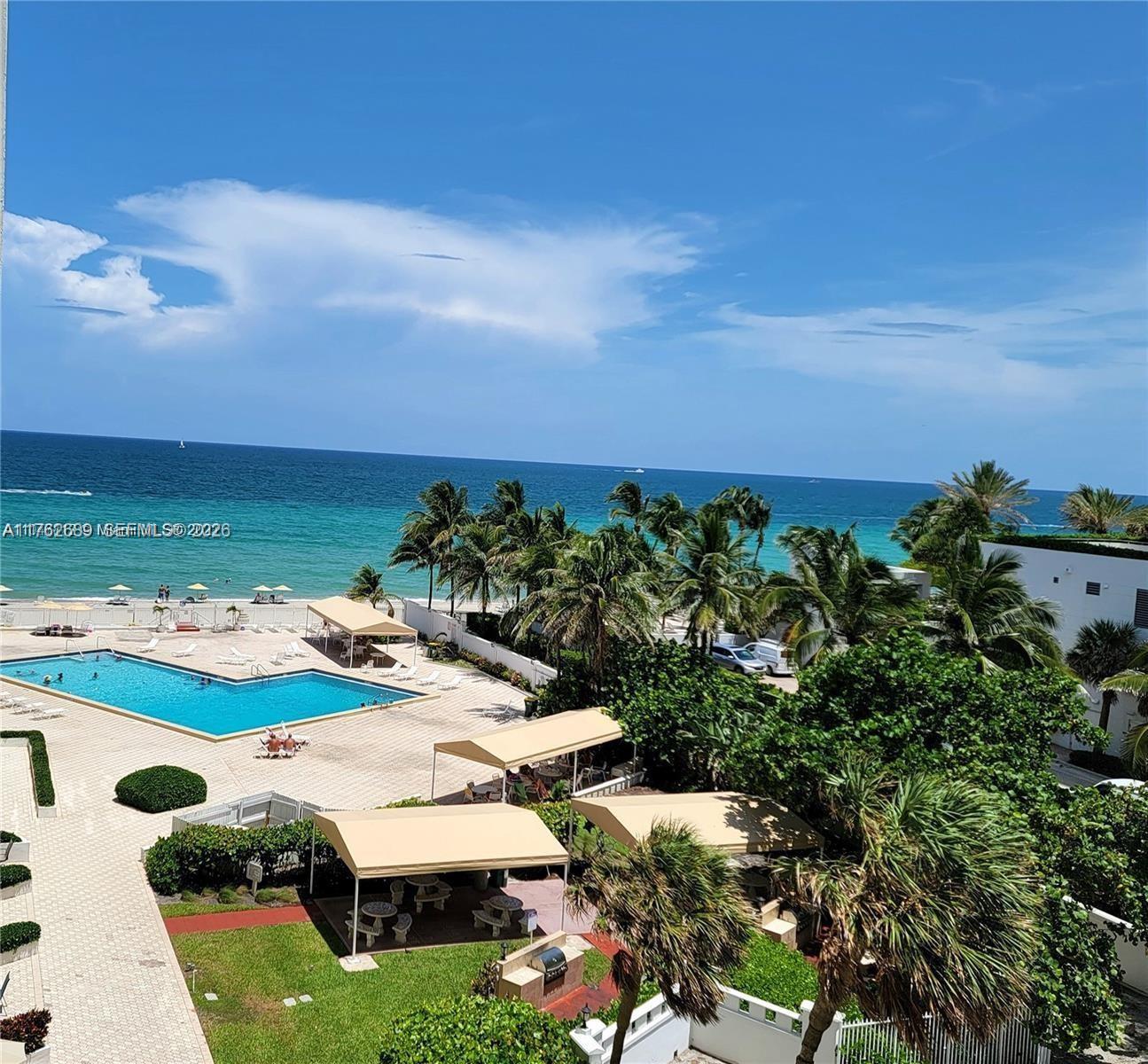 An elevated view shows a swimming pool, patio area, palm trees, and the ocean — 3505 S Ocean Dr # 819, Hollywood FL 33019, HOLLYWOOD, FL